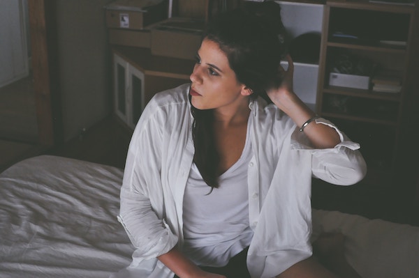 adult with lounge clothes sitting on a bed