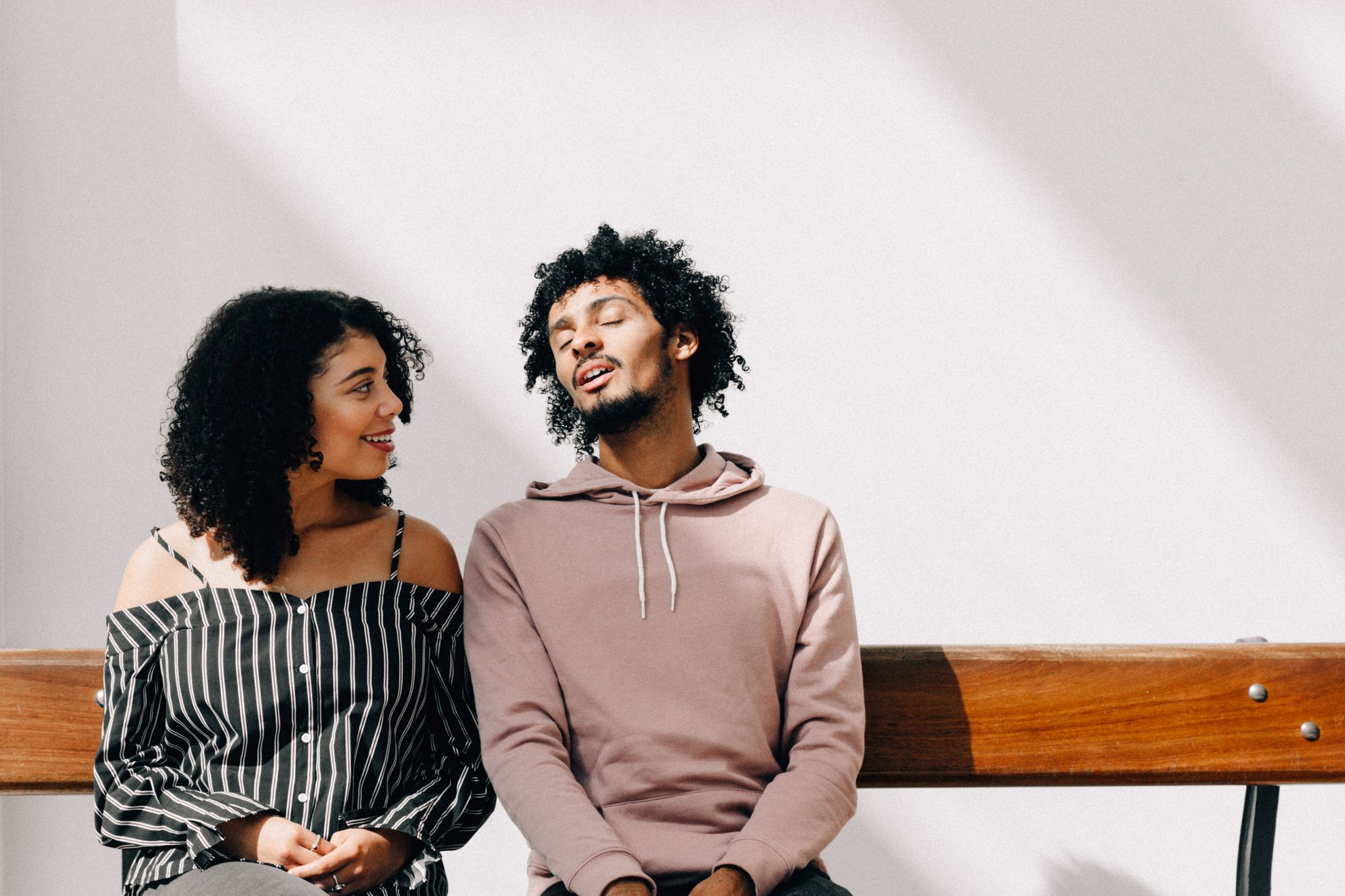 two people medium-skinned people sitting on a bench together