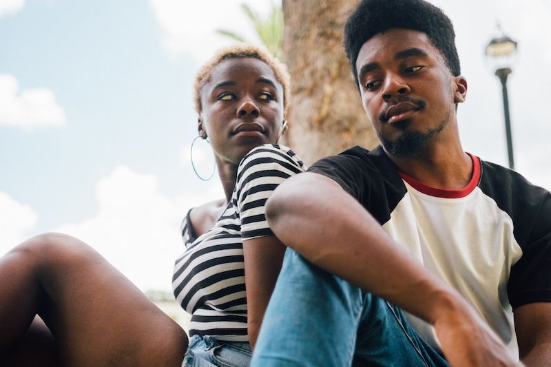 Straight couple sitting outside by a tree