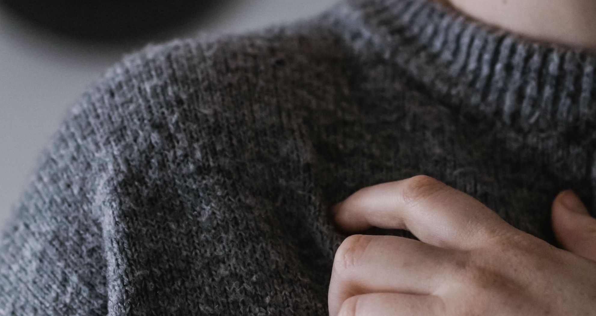 Close up of an adult wearing a dark grey knit sweater