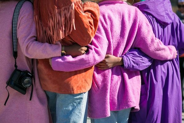 A group of people with dark skin standing side by side with their arms around each other