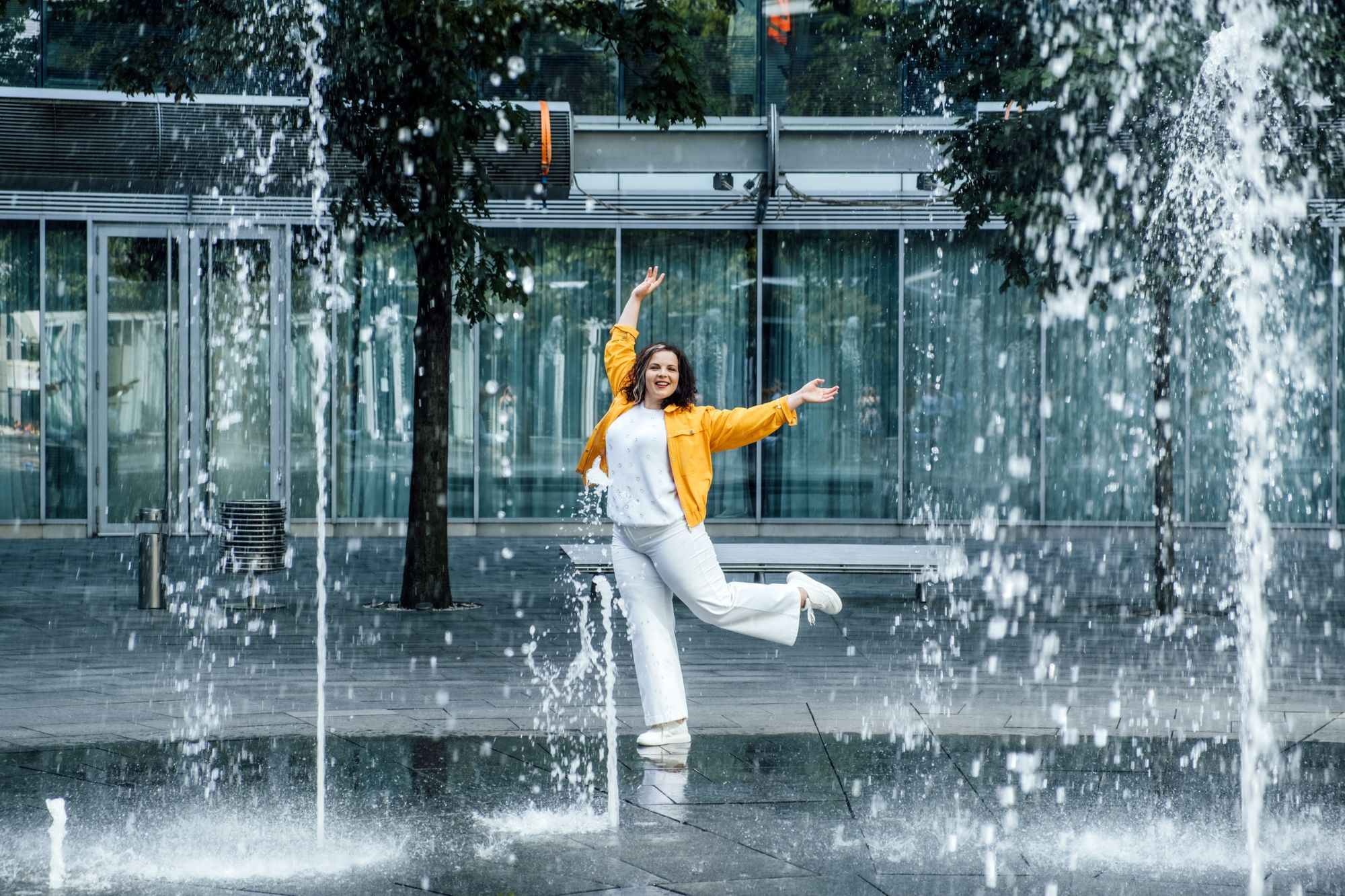Caucasian person outside in water splash area looking happy and carefree