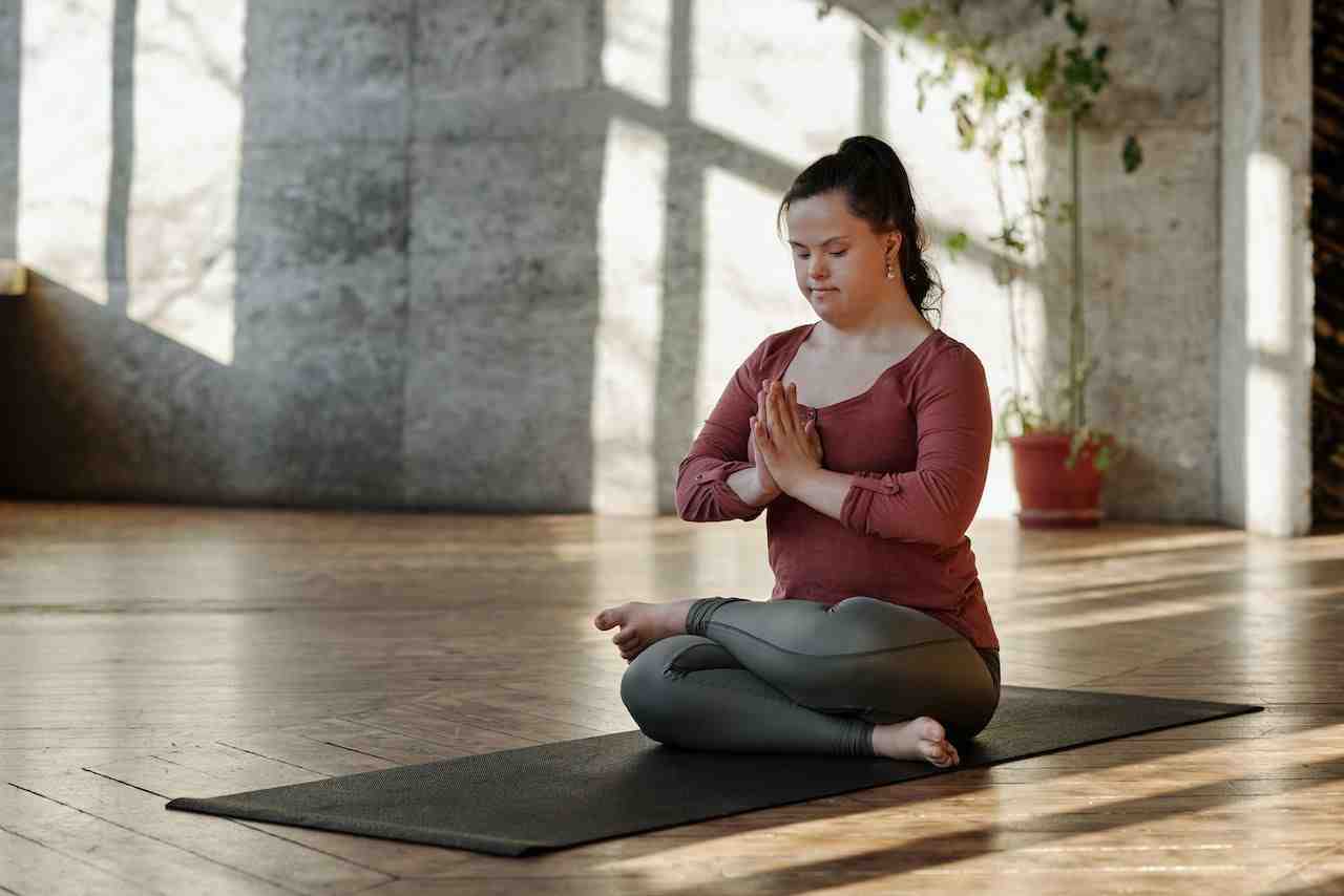 A light skinned person sitting on a yoga mat sitting in a yoga pose