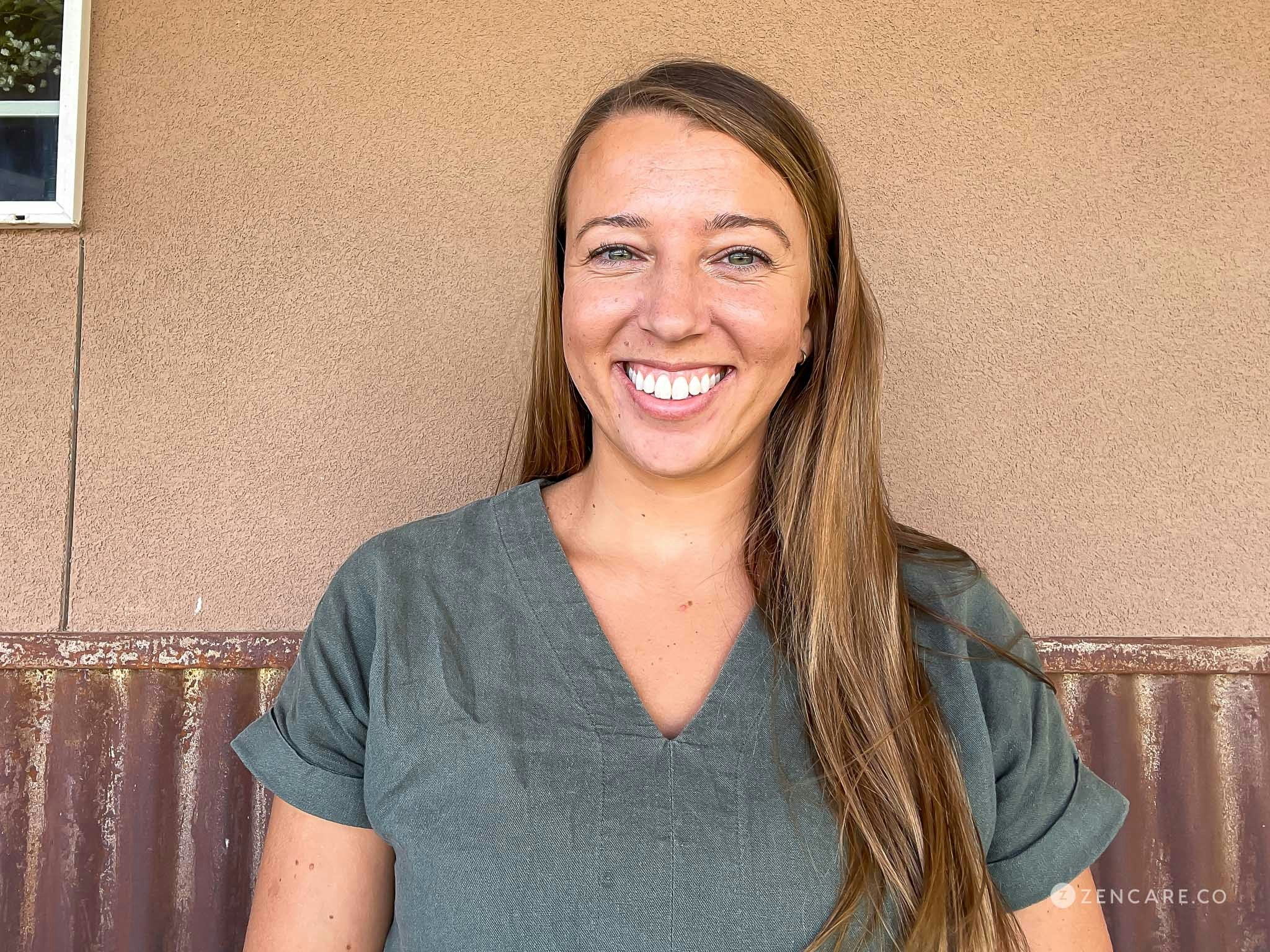 LPC Brooke Coffey sitting outside, looking at the camera smiling, and wearing a green/grey pull over blouse.