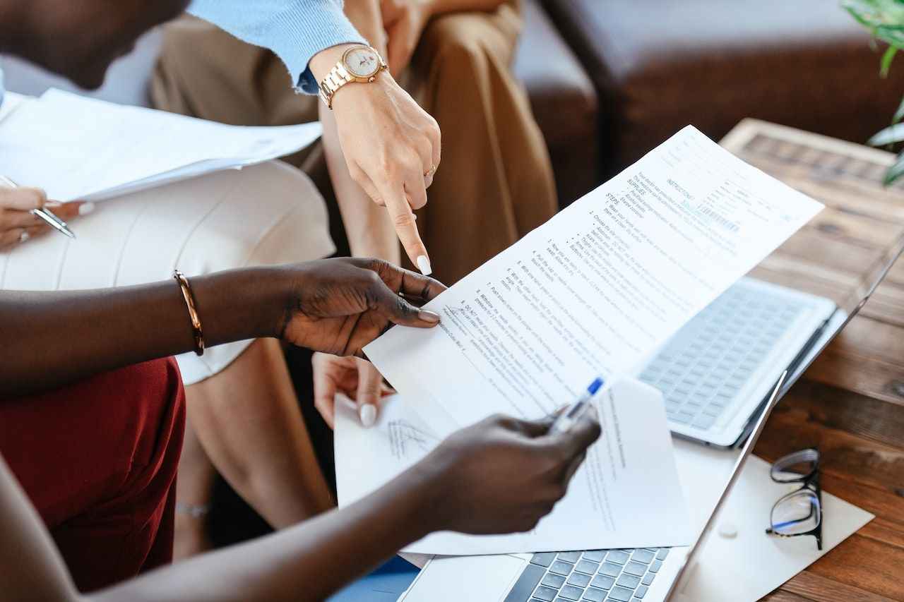 Documents being held and pointed at by a person with dark skin and a person with light skin