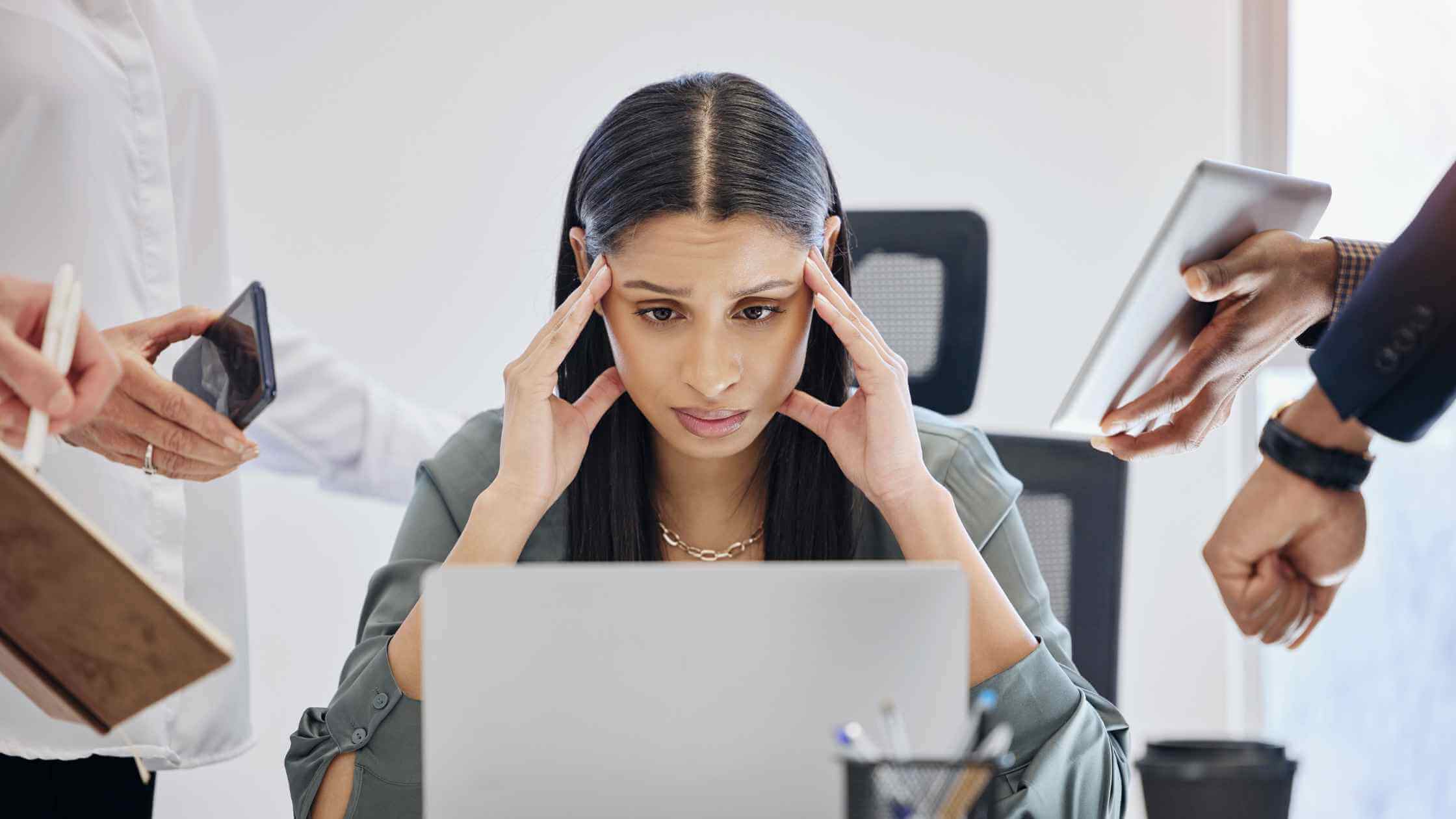 Medium-skinned adult staring at a laptop with an overwhelmed expression