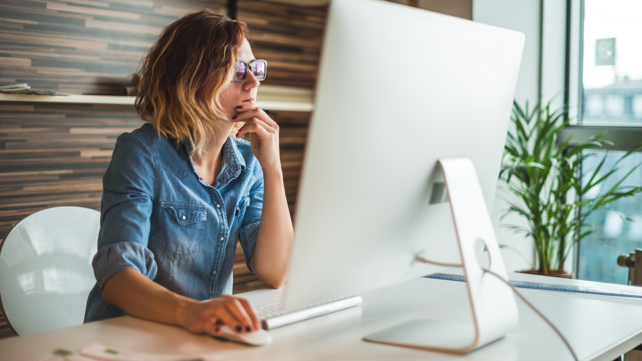 Caucasian person at a desk, looking at computer as if they are looking for something.