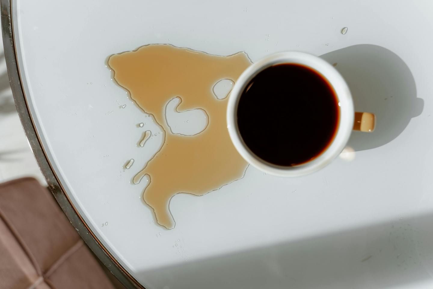 Coffee cup sitting on a table with coffee spilt on the table