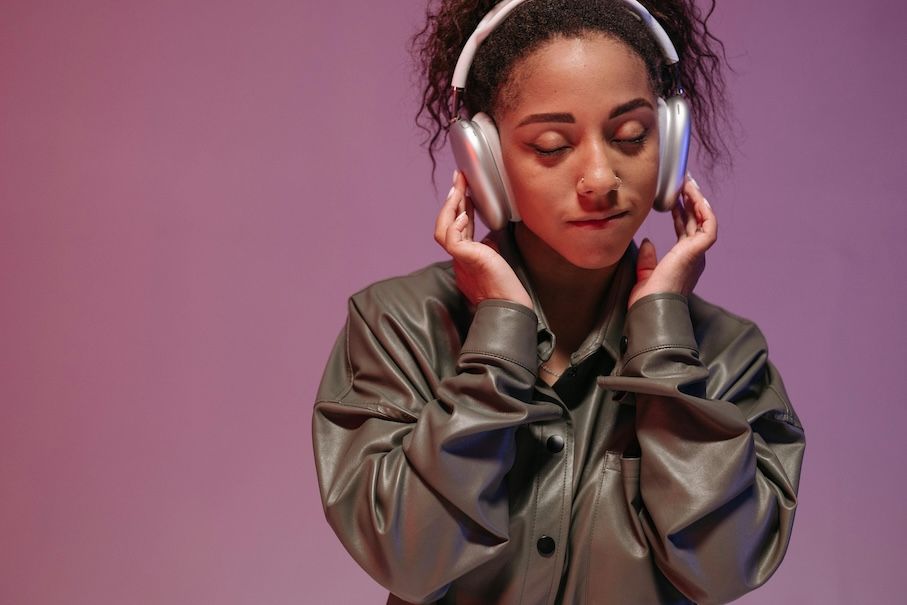 young adult wearing headphones, listening with their eyes closed