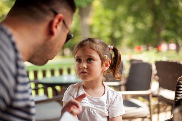 parent verbally disciplining a young child who looks upset