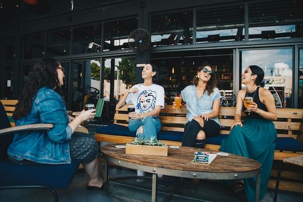 a group of adult friends laughing and drinking at a brewery