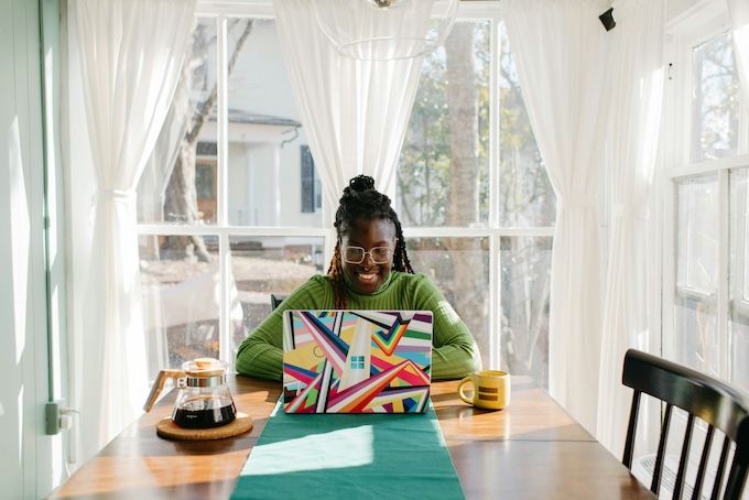 person wearing glasses sitting at a table with coffee and an open laptop